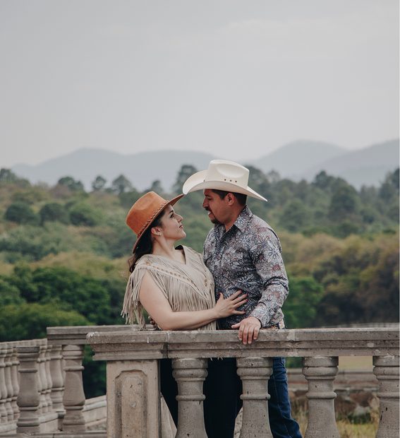 Pareja con sombreros vaqueros mirándose durante su sesión fotográfica