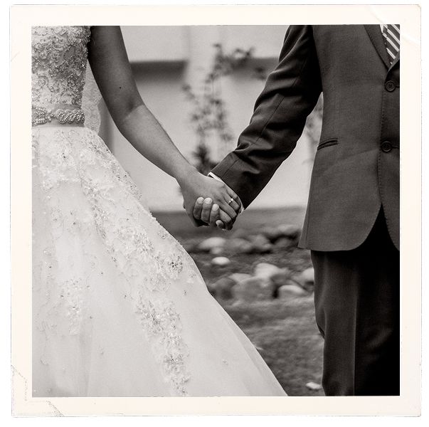 Manos entrelazadas de los novios con anillos de boda