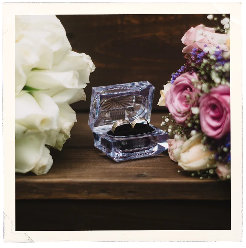 Anillos de boda en su caja junto a dos ramos de flores